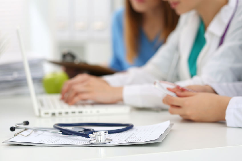 Clinical research associate with patient at desk