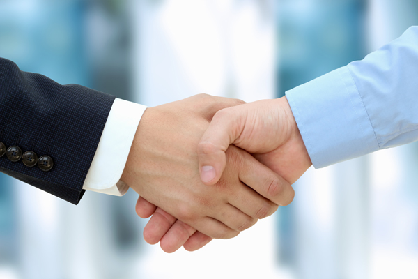 Close-up image of a firm handshake between two colleagues in office.