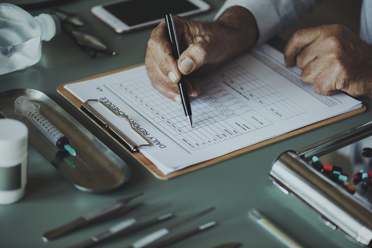Physician writing on daily patient report at desk