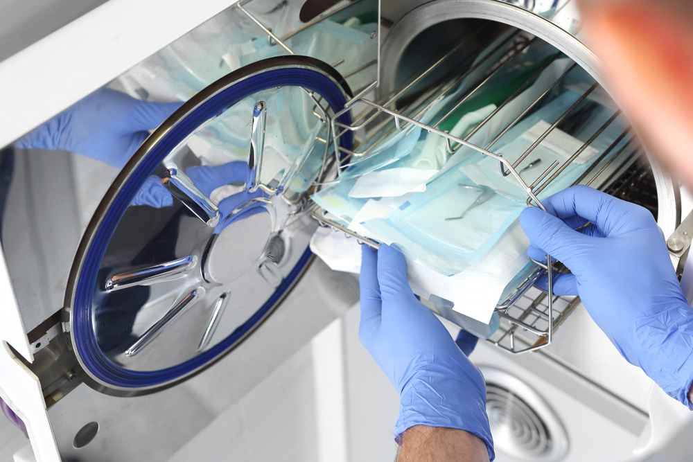 Doctor removing sterile medical instruments from autoclave