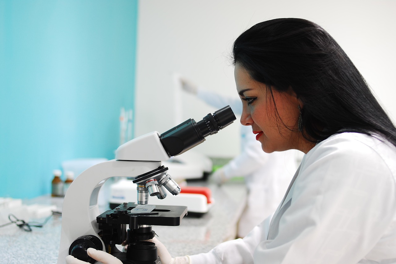 Woman peering through microscope, side profile